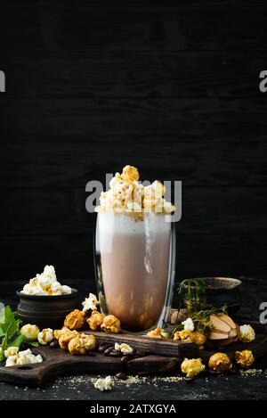 Kakao mit Milch und Popcorn. Im Glas. Draufsicht. Auf schwarzem Hintergrund. Stockfoto