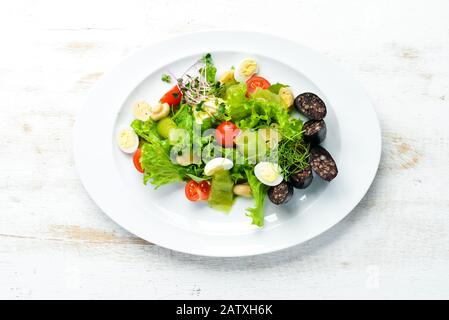 Salat mit Gemüse, Blutwurst und Pilzen auf einem Teller. Draufsicht. Freier Speicherplatz für Ihren Text. Rustikaler Stil. Stockfoto