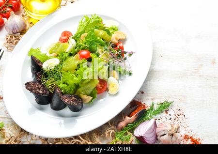 Salat mit Gemüse, Blutwurst und Pilzen auf einem Teller. Draufsicht. Freier Speicherplatz für Ihren Text. Rustikaler Stil. Stockfoto