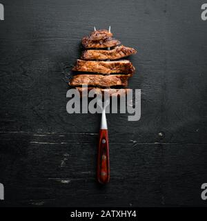 Schweinesteak auf der Gabel. Auf Holzgrund. Draufsicht. Freier Speicherplatz für Ihren Text. Stockfoto