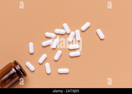 Film beschichtete weiße ovale Pillen aus der Flasche auf Pastellgrund mit Kopierraum, Draufsicht Stockfoto