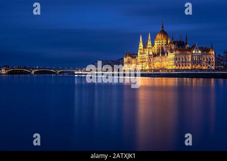 Ungarisches Parlamentsgebäude in Budapest nachts mit Donau-Fluss Stockfoto