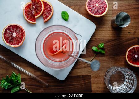 Mischung aus erfrischendem kaltem Sommercocktail und blutranger Farbe in einem Glaskrug auf einem Marmor-Tablett. Draufsicht, flache Laienzusammensetzung. Stockfoto