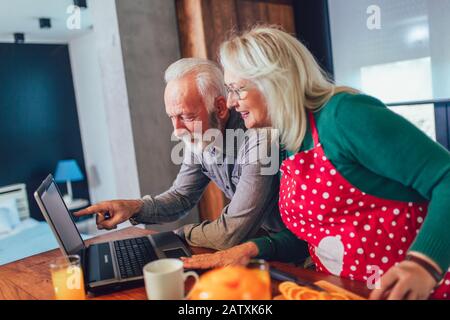 Glückliche Rentner, die gemeinsam auf einem Laptop im Internet surfen. Stockfoto