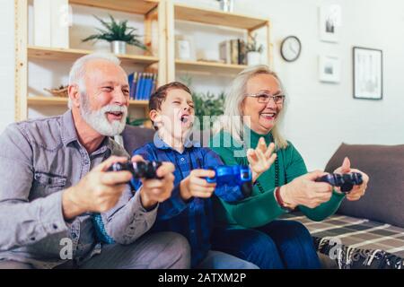 Der ältere Mann und die Frau spielen Videospiele, während ihr Enkel. Stockfoto