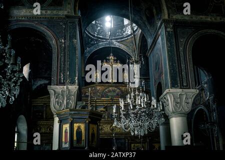 Athen - 6. Mai 2018: In einer alten orthodoxen Kirche in Athen, Griechenland. Dunkles Vintage-Interieur der griechischen Kirche. Ansicht des Altars mit Kreuz. Der Baufälligkeit Stockfoto