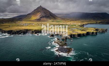 Luftstrohaufnahme von Arnastappi-Mänteln und Dorf mit Stapafell-Berg im Hintergrund, Snaefellsnes Peninsula, Island Stockfoto