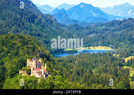 Schloss Hohenschwangau in Alpen, Bayern, Deutschland. Panoramasicht auf die schöne Burg mit Schwansee. Alpine Berglandschaft im Sommer. Pano Stockfoto