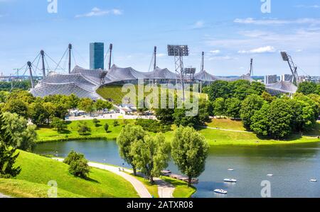 Münchner Olympiapark im Sommer, Deutschland. Blick auf Olympiastadion und See. Panorama auf das berühmte Münchner Sportgelände. Stadtbild Münchens mit bea Stockfoto