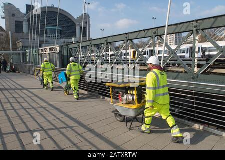 Drei Bauarbeiter, die schwere Ausrüstung in Schubkarren transportieren, Charing Cross, Central London, Großbritannien. 3 Ouvriers du bâtiment, Londres. Stockfoto