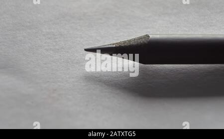 Graustufenbild eines spitzen Bleistifts auf einem Tisch mit einem undeutlichen Schatten, Nahaufnahme Stockfoto