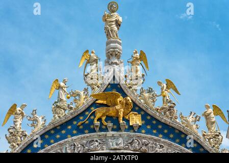 Markuselennig, Engel und der vergoldete Löwe auf der Spitze der Fassade des Markusdoms (Markusdom) in Venedig, Italien. Der geflügelte lio Stockfoto