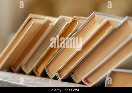 Regal in einem Buchladen mit Büchern für Spenden oder kostenlosen Austausch. Nahaufnahme einer Reihe von Büchern mit vergilbten Seiten. Selektiver Fokus. Ohne Menschen. Stockfoto