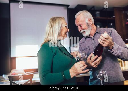 Älteres Paar verliebt sich in die Küche und trinkt Wein. Stockfoto