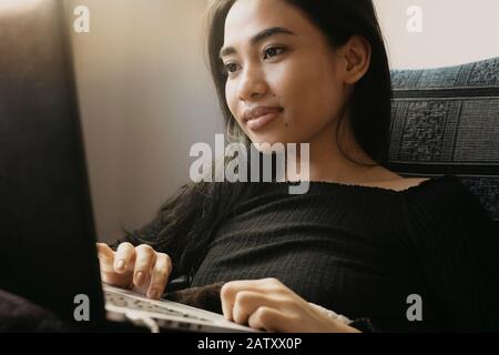 Schöne junge Frau, die zu Hause an einem Laptop arbeitet. Stockfoto