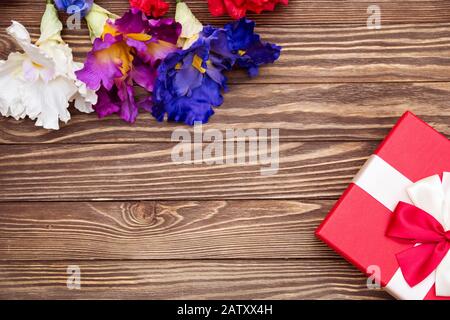 Echte Schachtel mit weißem und rotem Bogen und Band, Blick auf den Valentinstag isoliert auf Holzhintergrund. Kopierbereich für flache Lays Stockfoto