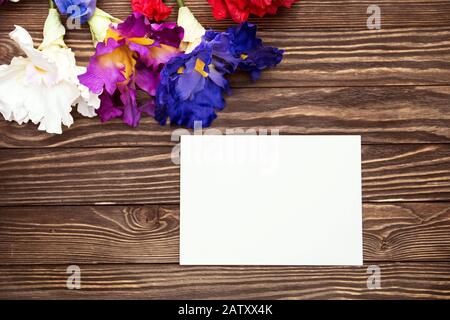 Weißer leerer Briefkopf und verschiedene Blumen Draufsicht am Valentinstag, isoliert auf einem Holzhintergrund. Kopierbereich. Stockfoto