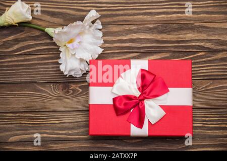 Echte Schachtel mit weißem und rotem Bogen und Band, Blick auf den Valentinstag isoliert auf Holzhintergrund. Flaches Lay. Kopierbereich Stockfoto