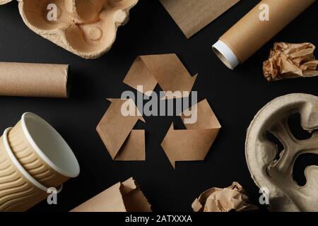 Recycling-Schild auf schwarzem Hintergrund mit anderem Papierkorb, Draufsicht Stockfoto