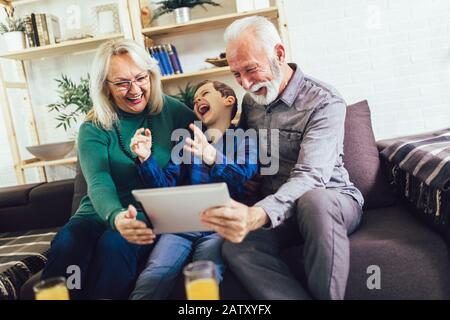 Der junge Junge, der seinen Großeltern neue Technologien zeigt Stockfoto
