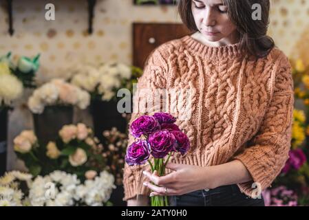 Der Blumenhändler hält in einem Blumenladen einen großen schönen Blumenstrauß des blühenden Ranunculus. Stockfoto