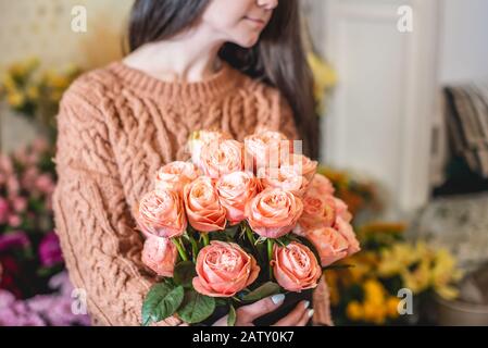 Der Blumenhändler hält in einem Blumenladen einen großen schönen Blumenstrauß mit blühenden rosa Rosen Stockfoto