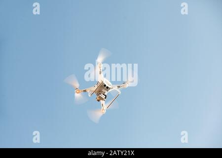 Ein Drohne oder Quadrocopter fliegt gegen einen blauen Himmel. Moderne Technologie zum Fotografieren und Filmen von Vogelperspektive. Stockfoto