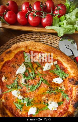 Blick in den hohen Winkel der italienischen Pizza mit Käse und Kirschtomaten auf dem Tisch Stockfoto