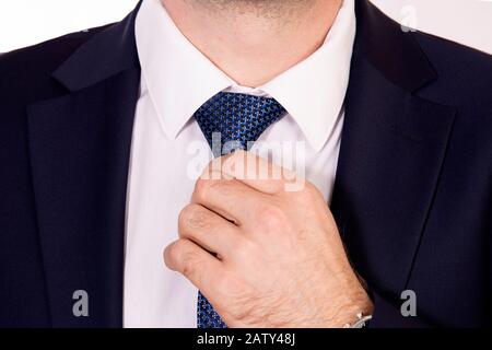 Ein Geschäftsmann in einem dunklen Anzug fixiert eine Krawatte Stockfoto