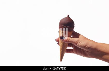 Auf weißem Grund wurde mit Schokolade überzogenem Eis in der Handfläche einer Frau gehalten. Stockfoto