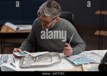 3D-Architekt arbeitet im Büro mit Farbpalette. Designer wählt Farben für das Bauen mit Farbfeldern aus, sucht nach neuen Ideen für Bauprojekte Stockfoto