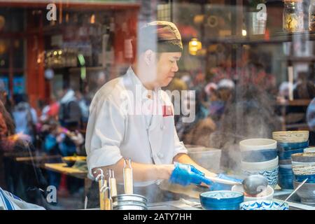 London, 26. Januar 2020. Blick auf das chinesische Restaurant durch Fenster, Küchenchef, Leute bei der Arbeit. Selektiver Fokus. Bewegungsunschärfe Stockfoto