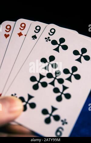 Person, die Karten mit einer Hand von vier Ninen spielt Stockfoto