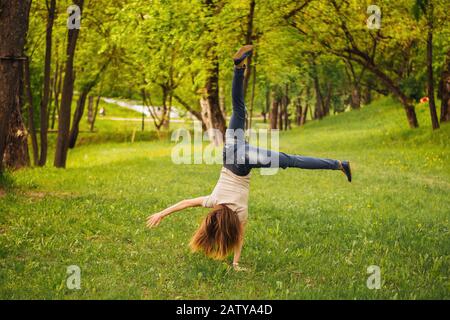 Mädchen macht ein akrobatisches Rad. Auf dem Gras. Stockfoto