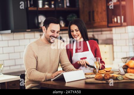 Schöne junge Paar ist die Verwendung eines digitalen Tablet und lächelnd beim Kochen in der Küche zu Hause. Stockfoto