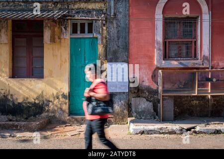 Fontainhas, Panaji, Goa, Indien - 27. Februar 2018: Unerkennbare Indianerin, die vor bunten Häusern im berühmten Stadtteil Fontainh spazieren geht Stockfoto