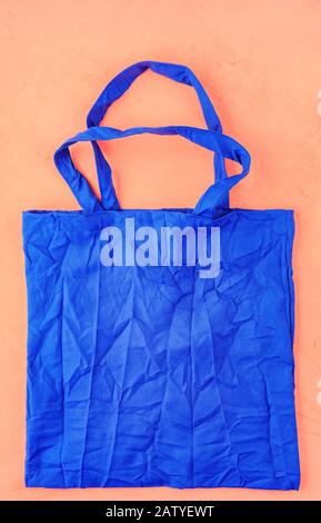 Umweltfreundliche Baumwolltasche in klassischer blauer Farbe vor pfirsichfarbenem Hintergrund. Null-Abfall-Konzept, plastikfreies, umweltfreundliches Einkaufen. Stockfoto