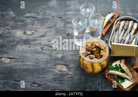 Sandwich mit Spritzen und Wodka. Spritt in Öl. Auf schwarzem Hintergrund. Draufsicht. Freier Speicherplatz. Stockfoto