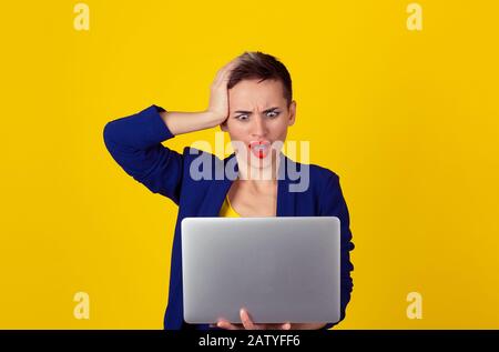 Ich wurde gehackt. Schockierte Geschäftsfrau mit Laptop auf Bildschirm isoliert gelber Hintergrund Wand blau Anzug menschliches Gesicht Ausdruck Emotionen f Stockfoto