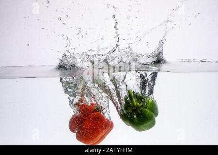 Drei Peppers fallen in Wasser. Wasser und Obst in ihr. Stockfoto