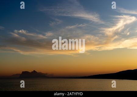 Atemberaubender Sonnenuntergang auf dem von Nebel umgebenen Felsen von Gibraltar, der von Spanien aus gesehen wird Stockfoto