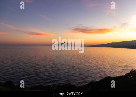 Atemberaubender Sonnenuntergang auf dem von Nebel umgebenen Felsen von Gibraltar, der von Spanien aus gesehen wird Stockfoto