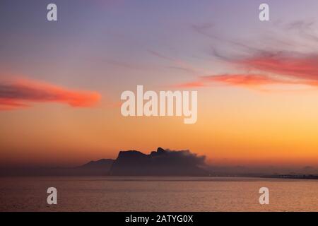 Atemberaubender Sonnenuntergang auf dem von Nebel umgebenen Felsen von Gibraltar, der von Spanien aus gesehen wird Stockfoto