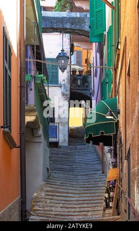 Gassen mit langen Treppenaufgängen, die bis auf die Höhe des Sees hinuntergehen, umgeben von hohen Gebäuden an den Seiten.Varenna - Italien Stockfoto