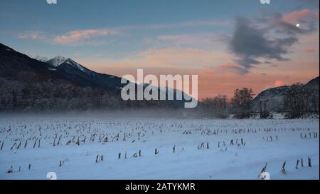 Bild eines Winteruntergangs über einem Feld in den Alpen. Stockfoto