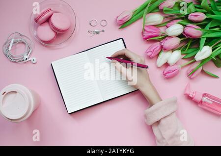 Mädchen, die eine Wunschliste für zukünftige Pläne schreiben: Flache Laienzusammensetzung mit Blumen, Notizblock, Tasse Kaffee und Süßigkeiten Stockfoto