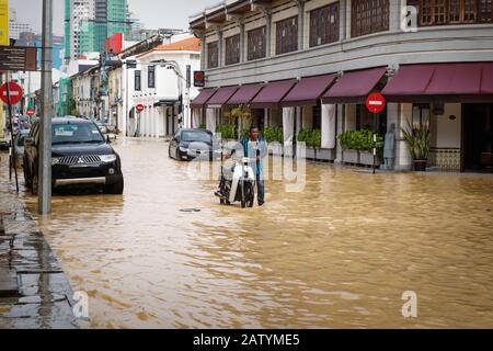 Georgetown, Penang, Malaysia - 5. November 2017: Lokaler Mann treibt nach starkem Regen das Motorrad durch die braun überflutete Straße Stockfoto