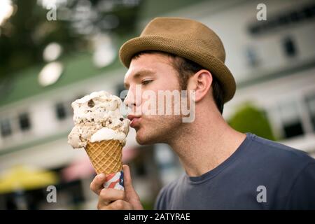 Mann, der einen riesigen Eiskegel isst. Stockfoto