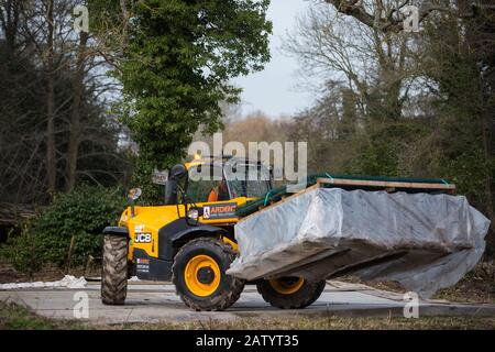 Denham, Großbritannien. Februar 2020. Ein JCB-Gabelstapler transportiert das Fechten über eine provisorische Fahrbahn im Buckinghamshire Golf Club im Colne Valley für Arbeiten, die in Verbindung mit der Hochgeschwindigkeitsstrecke HS2 geplant sind, einschließlich dem Fällen alter Bäume in einem Naturreservat auf der anderen Seite des Flusses Colne und dem Bau Einer Bailey-Brücke über den Fluss. Umweltaktivisten besetzen im Denham Country Park Bäume, um die Arbeit zu verhindern oder zu behindern. Credit: Mark Kerrison/Alamy Live News Stockfoto