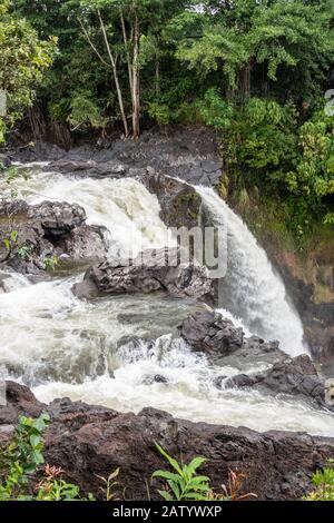 Hilo, Hawaii, USA. - 14. Januar 2020: Nahaufnahme von weißem Wasser und Lavagesteinen am Rande der Rainbow Falls. Grüne Vegetation. Stockfoto